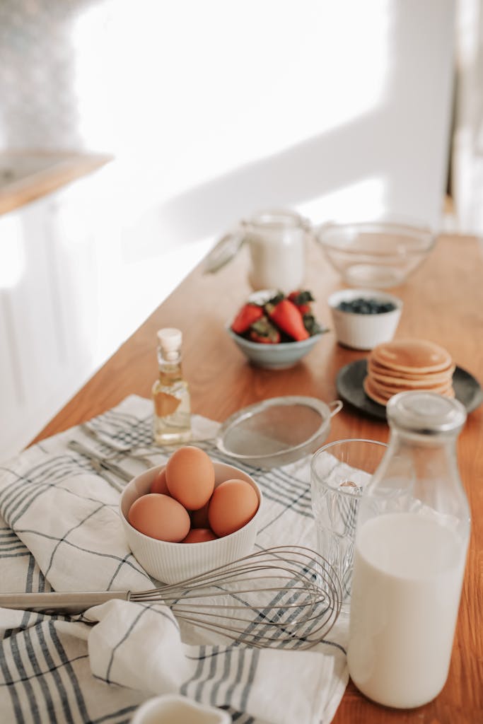 A cozy morning scene with eggs, milk, and fresh ingredients on a wooden table.