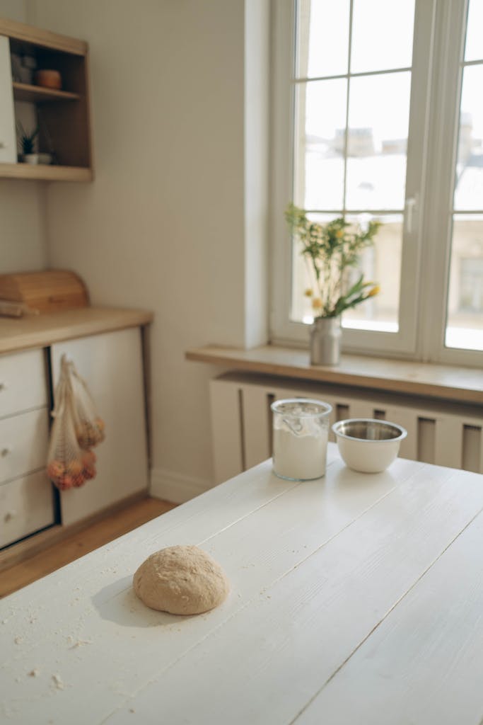 A warm kitchen scene with dough and ingredients on a sunlit counter.