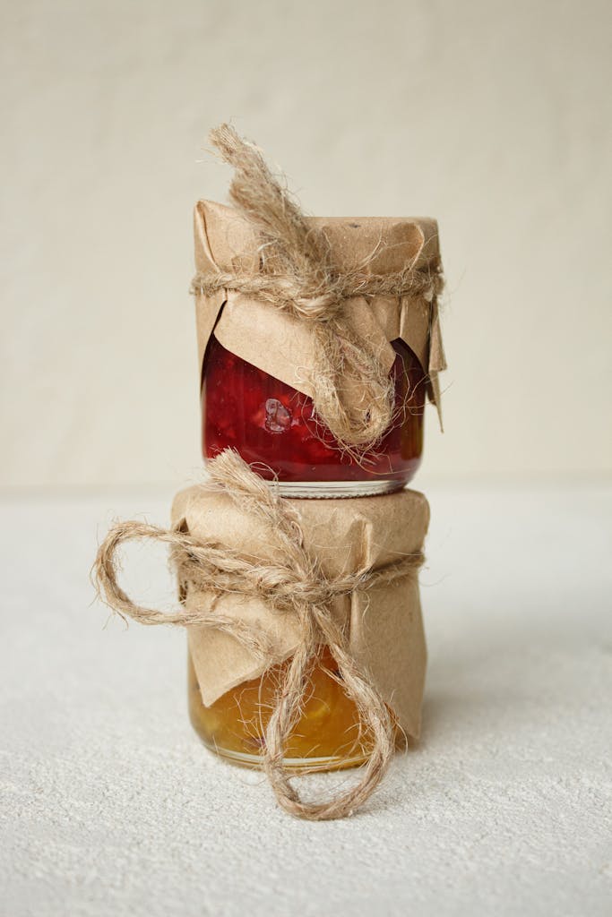 Close-up of stacked jars of homemade jams wrapped in rustic paper and twine.