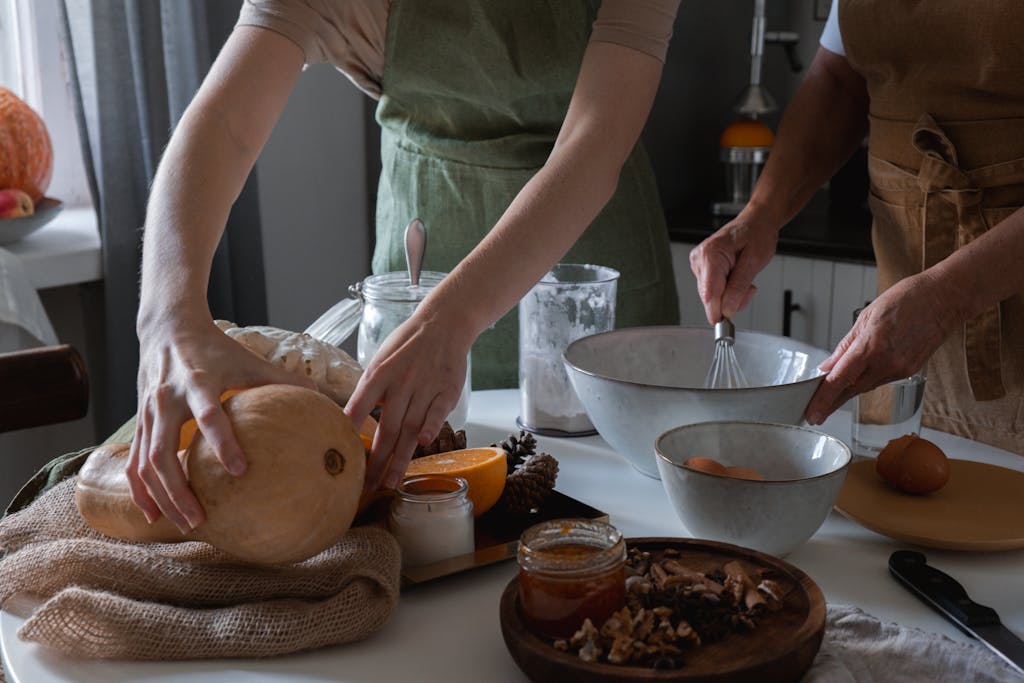 Two adults preparing food with squash in a cozy kitchen, showcasing a warm, autumn atmosphere.