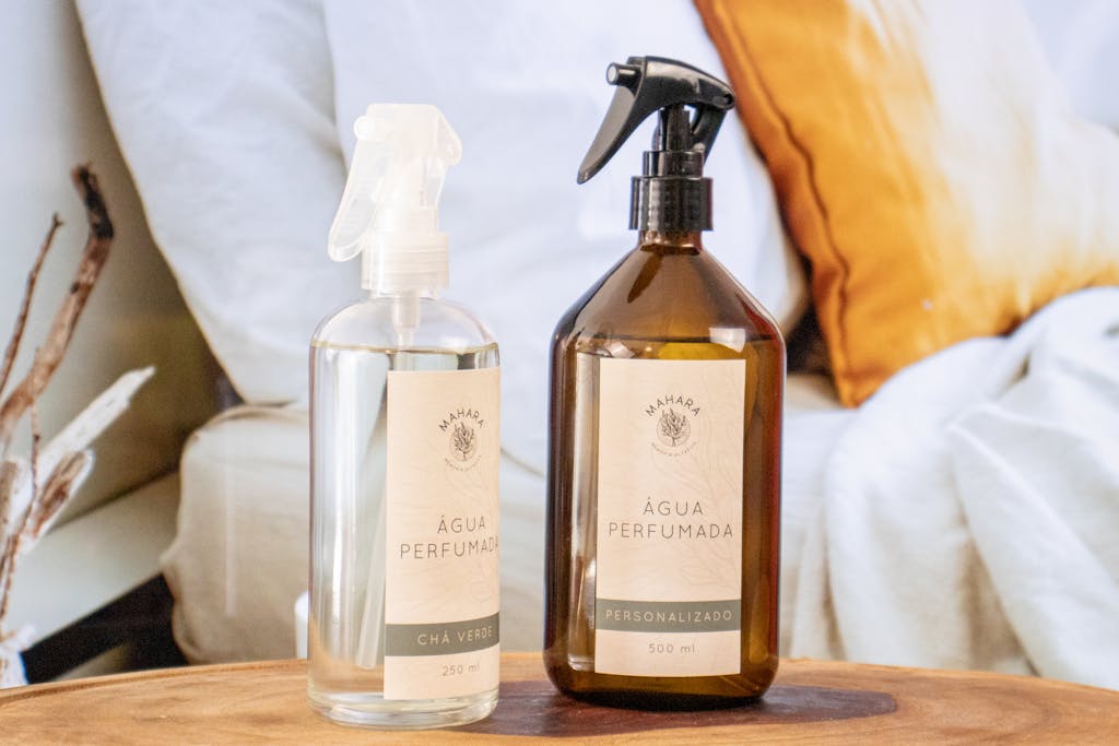 Two fragrant spray bottles placed on a wooden table in a cozy indoor setting.